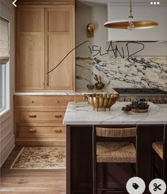 a kitchen with marble counter tops and gold accents on the cabinets, along with two stools