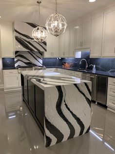 a kitchen with marble counter tops and white cupboards, an island in the middle