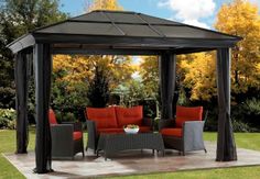 a gazebo sitting on top of a patio covered in red cushions and black curtains