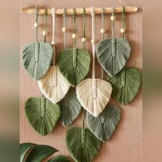 green and white leaves hanging on a wall next to a potted plant with wooden beads