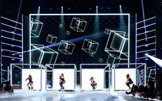 the dancers are performing on stage in front of large screens with cubes behind them