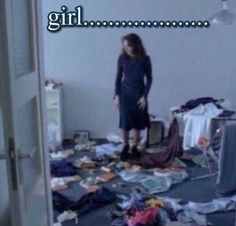 a woman standing in a messy room with clothes scattered all over the floor and walls