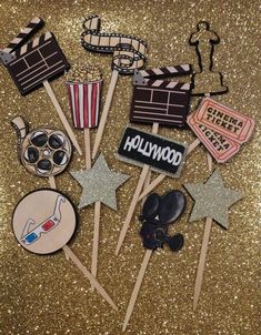 hollywood themed cupcake toppers on a gold glitter background with stars and clapsticks