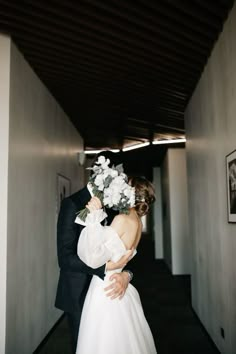 a bride and groom are kissing in an empty hallway with white flowers on their head