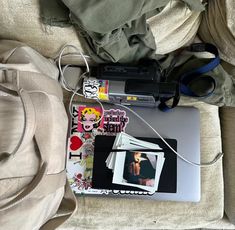 an open laptop computer sitting on top of a bed next to a bag and headphones