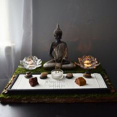 a buddha statue sitting on top of a tray filled with rocks