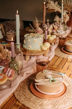 a table topped with lots of cake next to candles and other food on top of plates