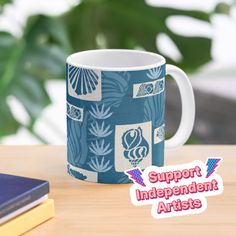 a blue and white mug sitting on top of a wooden table next to a book