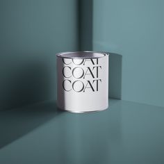 a white can sitting on top of a table next to a purple wall with the word coat over it