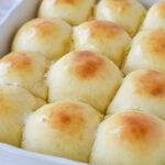 a white dish filled with rolls covered in cheese