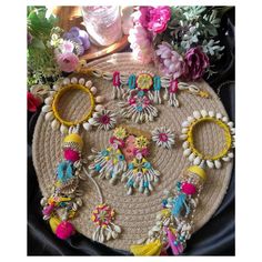 an assortment of jewelry is displayed on a round mat with flowers and other items around it