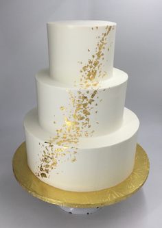 a three tiered white cake with gold sprinkles