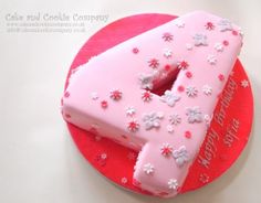 a pink cake with white flowers and the letter e on it's side, sitting on top of a red plate