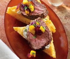 two slices of steak with mango salsa on cornbread crusts and garnished with sour cream