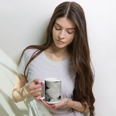 a young woman holding a coffee mug in her right hand and looking down at it