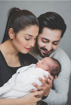 a man and woman holding a baby in their arms