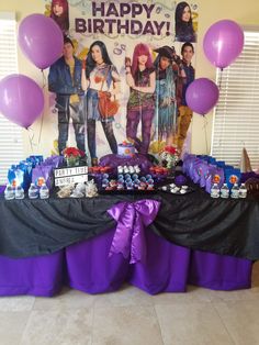 a birthday party with purple and black table cloths, balloons and pictures on the wall