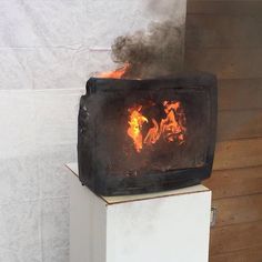 a stove that is on top of a white box with fire coming out of it