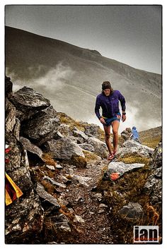 a man running up a rocky trail in the mountains