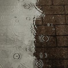 an umbrella is reflected in the water next to brick walkways and cobblestone pavement