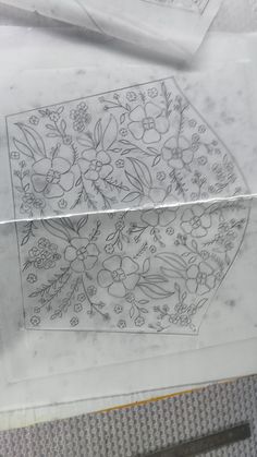 a piece of paper that has been drawn with flowers and leaves on it, sitting next to a pair of scissors