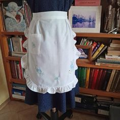 a white apron on a mannequin in front of a book shelf with books