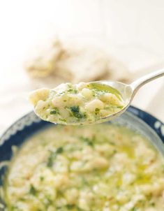 a spoon full of food with broccoli and cheese on it, in a bowl