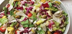 a salad with lettuce, tomatoes and onions in a white bowl on a table