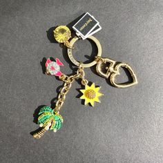 a keychain with various charms on it sitting on a gray surface next to a card