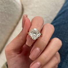 a woman's hand holding a ring with a diamond on it and the middle finger