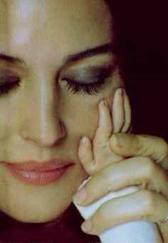 a close up of a woman holding her hand to her face