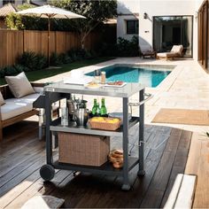 an outdoor bar cart with drinks on it next to a swimming pool and patio furniture