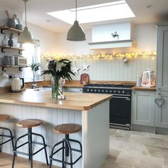 a kitchen with two stools next to an island and lights on the back wall