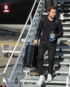 a man walking up the stairs with his luggage and water bottle in front of him