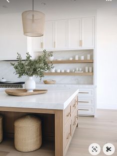 a kitchen with white cabinets and counter tops, an island in the middle has two stools on it