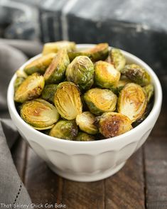 a white bowl filled with brussel sprouts on top of a wooden table