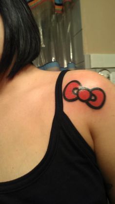 a woman with a tattoo on her shoulder that has a red and black bow in it