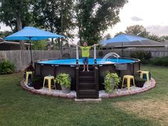 a young boy standing on the edge of a swimming pool surrounded by lawn chairs and umbrellas