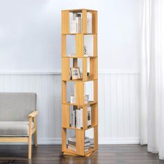 a tall wooden shelf with books on it in a living room next to a chair