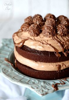 a chocolate cake with frosting and chocolate candies on top is sitting on a blue plate