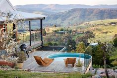 a wooden deck with two chairs next to an above ground swimming pool in the mountains