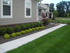 a house that has some plants in front of it and grass on the ground next to it