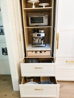 an open cabinet with two drawers containing coffee pots and pans on the bottom shelf