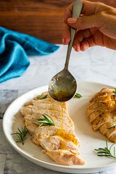 someone is drizzling sauce onto some food on a white plate with silverware