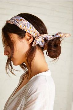 a woman wearing a bandana with her hair in a ponytail and looking off to the side