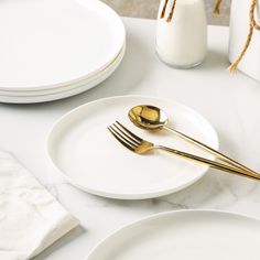 two white plates with gold forks on them