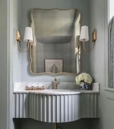 a bathroom sink with a mirror above it and two lamps on the wall next to it