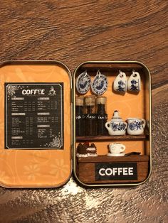 an open tin with coffee items in it on a wooden table next to a cup and saucer