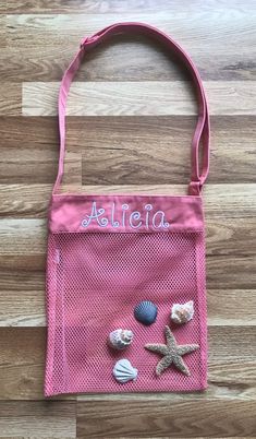 a pink handbag with seashells and starfish on the inside, sitting on a wooden floor