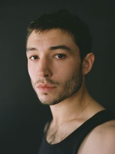 a man in black tank top looking at the camera with serious look on his face